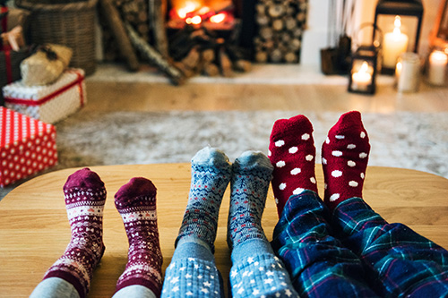 family with socked feet by the fireplace